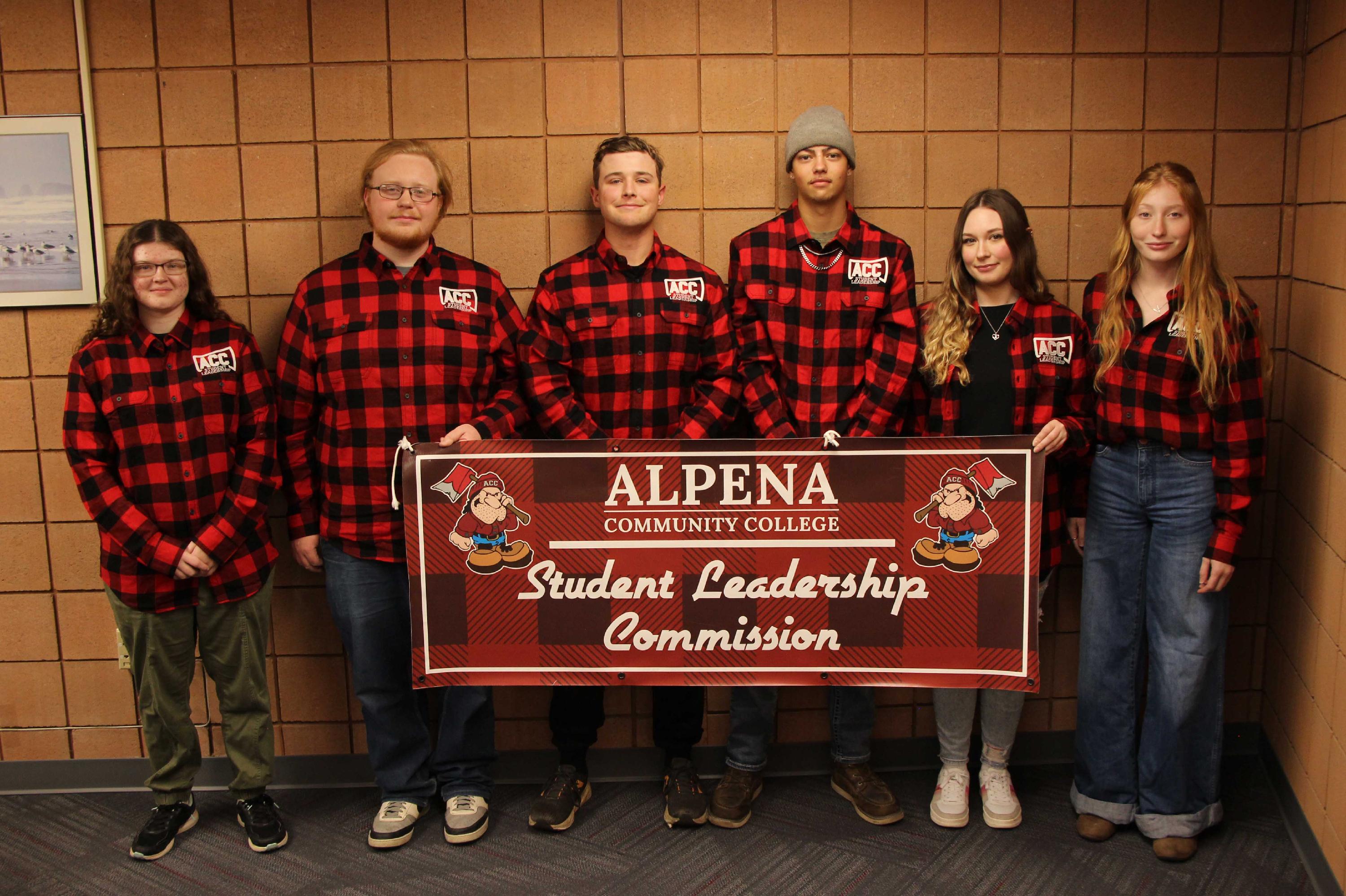 The Student Leadership Commission group stands and poses for a picture while holding a banner
